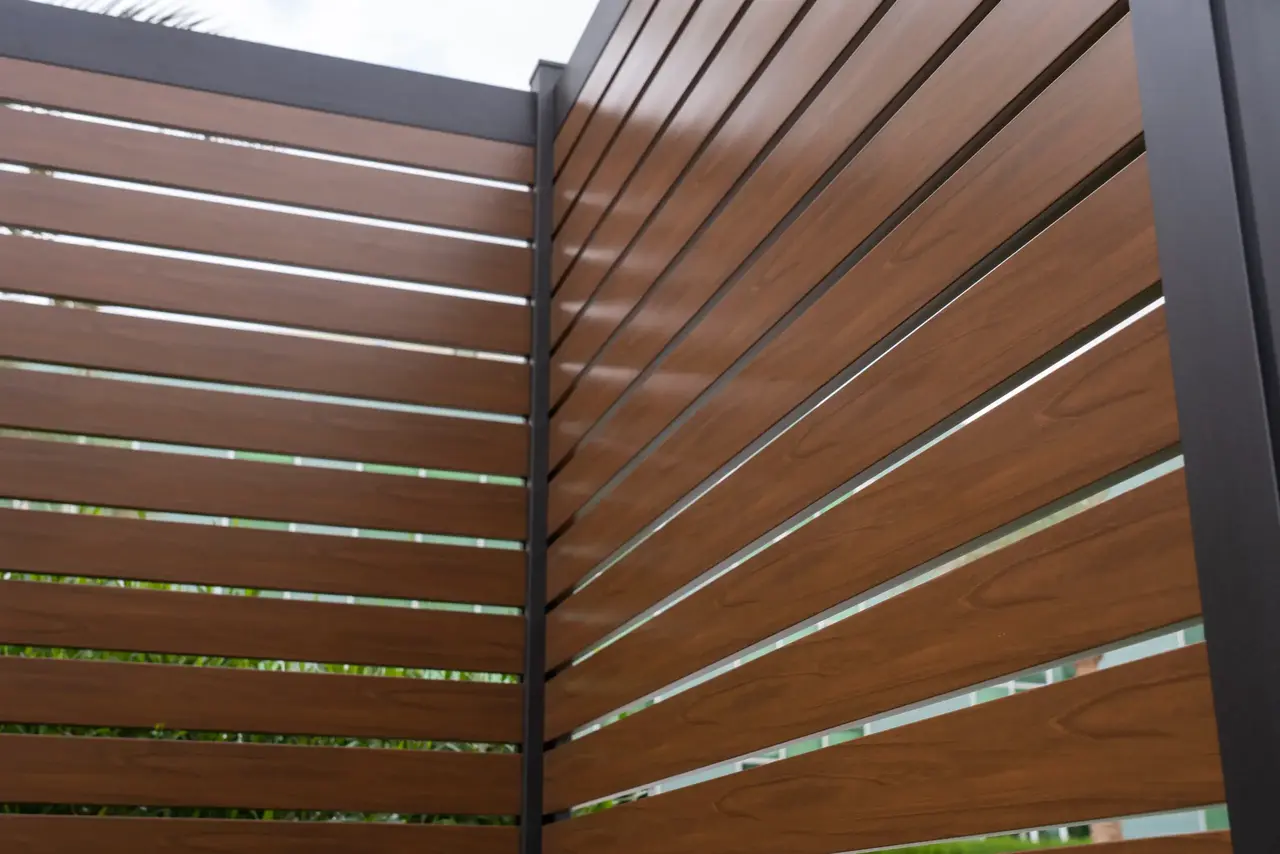Close-up of a walnut wood-grain horizontal aluminum privacy fence panel