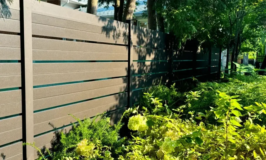 Walnut wood-grain horizontal aluminum privacy fence in a landscaped garden