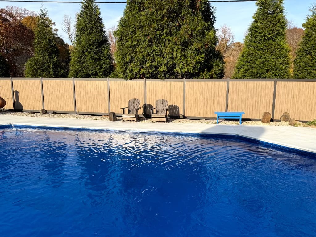 Vertical-slat aluminum privacy fence and gate enclosing a backyard pool area